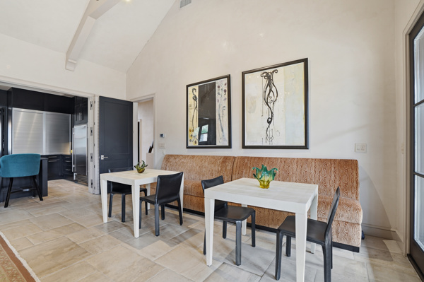 Casual dining nook with woven banquette, vaulted ceiling, and abstract art on stucco walls