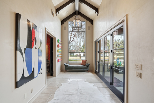 Dramatic entry gallery with vaulted beamed ceiling, stone floor, lantern pendant, and contemporary art